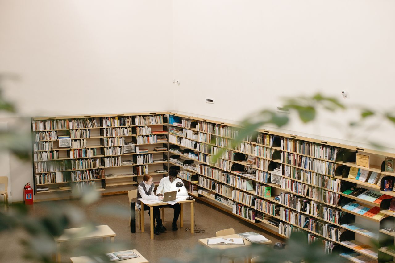 Students studying together at a library with laptops and books.