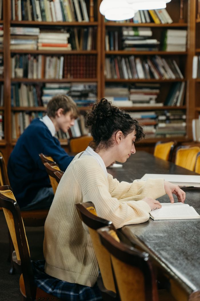Young adults immersed in reading and study in a cozy library environment.